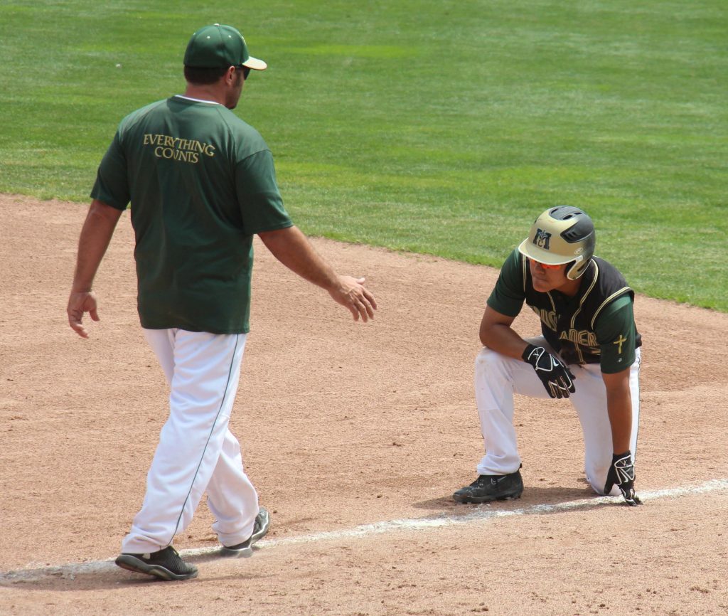 Norberto Vasquez kneels after getting out at first while coach Mike Holt goes to talk with him. Photo/Dave Hart 
