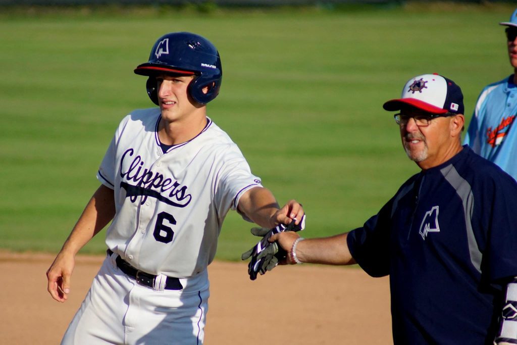 Jacob Buchberger reaches base safely and hands his batting gloves to coach Brian Wright. Photo/Leo Valdez